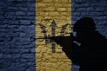 Soldier silhouette on the old brick wall with flag of barbados country.