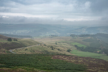 Obraz premium Stunning landscape image of the view from Higger Tor in the Peak District National Park in Egnland with light fog across the rolling fields
