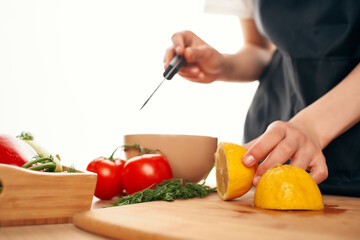 chef with a knife in his hands cuts vegetables and lemon kitchen home cooking