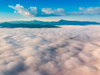 High flight over the fog in the mountains. Ukrainian Carpathians in the morning. Aerial drone view.