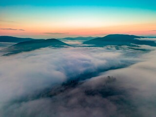 Fog in the mountain valley at dawn. Ukrainian Carpathians in the morning in the haze. Aerial drone view.