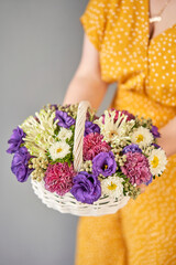 Flower arrangement in Wicker basket. Beautiful bouquet of mixed flowers in woman hand. Handsome fresh bouquet. Small flower shop and Flowers delivery.