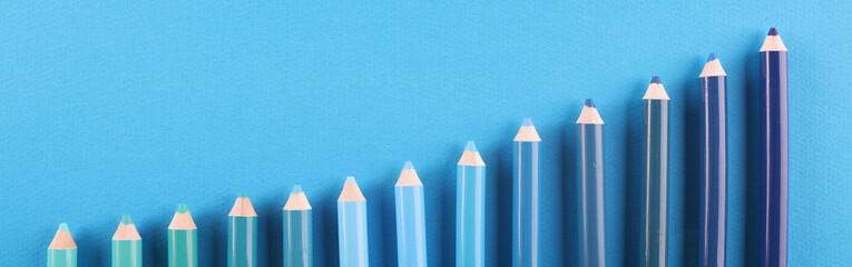 Pencils of different shades lie on blue background