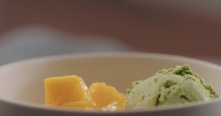 green ice cream in white bowl with ripe mango