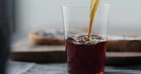 pour cold brew coffee in tumbler glass on walnut table