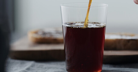 pour cold brew coffee in tumbler glass on walnut table
