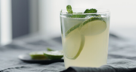 decorate lemonade with mint leaves in tumbler glass on linen cloth