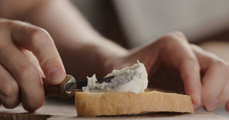 spread cream cheese on fresh ciabatta slice on olive board closeup