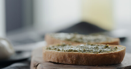 spread pesto on fresh ciabatta slice to make sandwich closeup