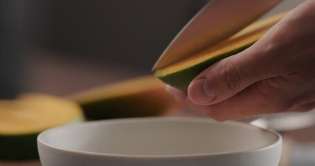 man cut ripe red mango on olive wood board