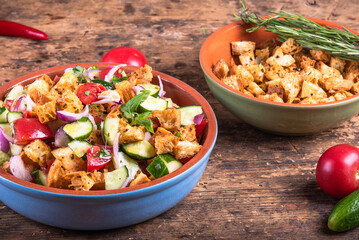 Italian panzanella salad with ciabatta croutons on the table in a bowl - a beautiful multicolored vegetarian dish