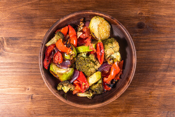 Baked colorful vegetables - broccoli, tomatoes, peppers, zucchini. Serving vegetable stew in a plate, top view