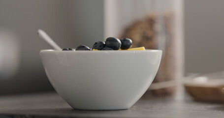 blueberries and mango in white bowl on terrazzo countertop
