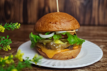 Close-up of a standard burger. Adult fast food in a restaurant or cafe. Macro photo of burger ingredients with meat, cheese and herbs. Eco burgers for the whole family