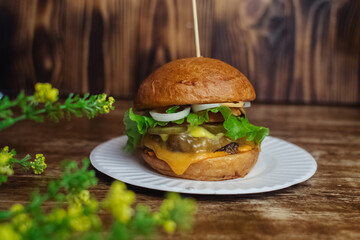 Close-up of a standard burger. Adult fast food in a restaurant or cafe. Macro photo of burger ingredients with meat, cheese and herbs. Eco burgers for the whole family