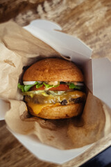Close-up of a standard burger. Adult fast food in a restaurant or cafe. Macro photo of burger ingredients with meat, cheese and herbs. Eco burgers for the whole family