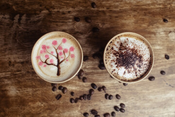 Obraz na płótnie Canvas Drawings on coffee. Male and female cappuccino decoration. Hot drink in a paper cup. Picture of a chocolate mountain and Japanese cherry blossom. Food industry creativity concept