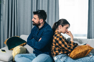 Young couple are arguing on the couch in their home and having difficulty and problems in a...