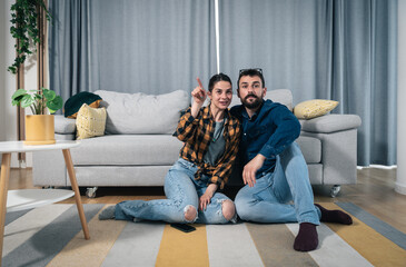 Naklejka premium Couple watch television show and man fake that he is interested while woman explaining to him who is who and what is the theme of that tv show, couple bonding concept