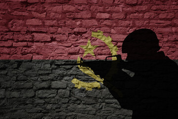 Soldier silhouette on the old brick wall with flag of angola country.