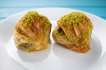 Traditional Turkish pastry dessert Baklava on the white plate, and blue table background.