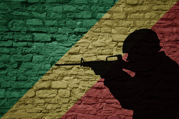 Soldier silhouette on the old brick wall with flag of republic of the congo country.