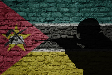 Soldier silhouette on the old brick wall with flag of mozambique country.
