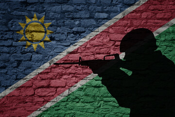Soldier silhouette on the old brick wall with flag of namibia country.