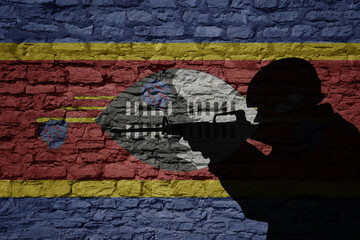 Fototapeta premium Soldier silhouette on the old brick wall with flag of swaziland country.