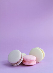 Macaron or macaroon on lilac background, colorful almond cookies with different fillings