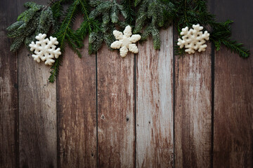 Obraz na płótnie Canvas christmas border with white snowflakes, pine cones, and green branches on a rustic, old, wooden background, vintage style