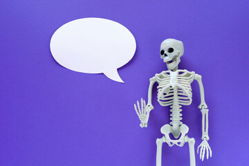 Skeleton on violet background with white blank paper ellipse speech bubble. Anatomical plastic...
