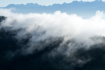 clouds passing above a crest and mountains in the background