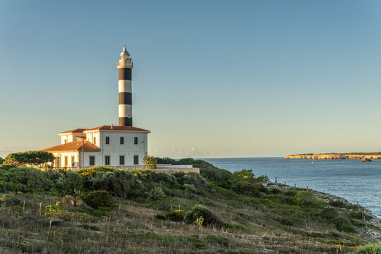 General view of the lighthouse of the Majorcan town of Portocolom, at dawn on a sunny day. Maritime navigation image