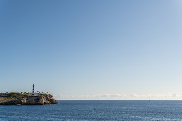 General view of the lighthouse of the Majorcan town of Portocolom, at dawn on a sunny day. Maritime navigation image
