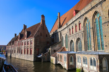 Fototapeta na wymiar Brugge (Sint Jans Hospital), Belgium - October 9. 2021: View over water canal on medieval brick gothic hospital building