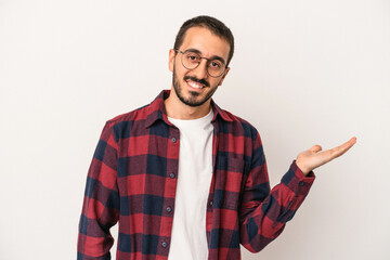 Young caucasian man isolated on white background showing a copy space on a palm and holding another...