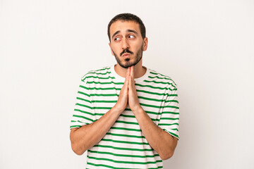 Young caucasian man isolated on white background praying, showing devotion, religious person looking for divine inspiration.