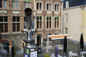 Gent (St. michaels bridge), Belgium - October 9. 2021: Closeup of monocular telescope on bridge at tourist view point, blurred medieval buildings background