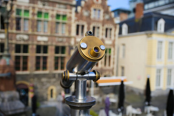Gent (St. michaels bridge), Belgium - October 9. 2021: Closeup of monocular telescope on bridge at tourist view point, blurred medieval buildings background