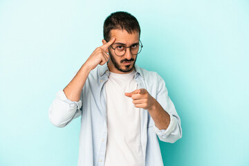 Young caucasian man isolated on blue background pointing temple with finger, thinking, focused on a task.