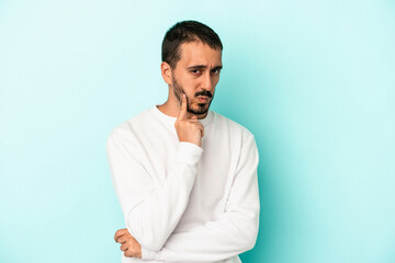 Young caucasian man isolated on blue background contemplating, planning a strategy, thinking about the way of a business.