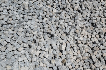 Close up of a pile of loose paving stones before being set into a cobblestone road.