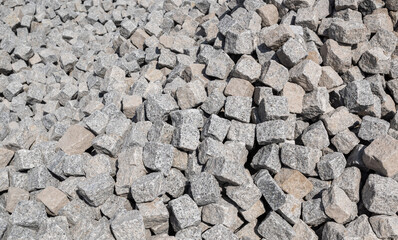 Close up of a pile of loose paving stones before being set into a cobblestone road.