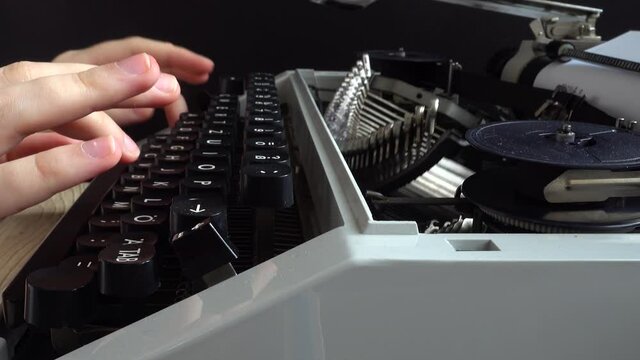 The girl is typing on a retro typewriter.