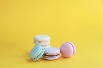 Macaron or macaroon on yellow background, colorful almond cookies with different fillings