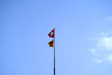 Swiss flag and flag of Canton Schaffhausen blowing in the wind at Village of Neuhausen am Rheinfall. Photo taken September 25th, 2021, Neuhausen am Rheinfall, Switzerland.