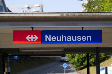 Obraz premium Blue sign at railway station Neuhausen on a cloudy autumn day. Photo taken September 25th, 2021, Neuhausen am Rheinfall, Switzerland.