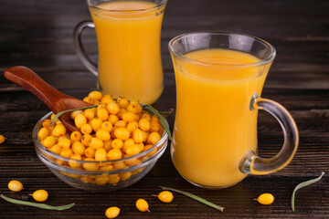 Sea buckthorn juice with honey in glass cups on a wooden background.