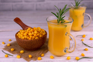 Sea buckthorn smoothie with honey in glass cups on a white wooden background. Vitamin cocktail.